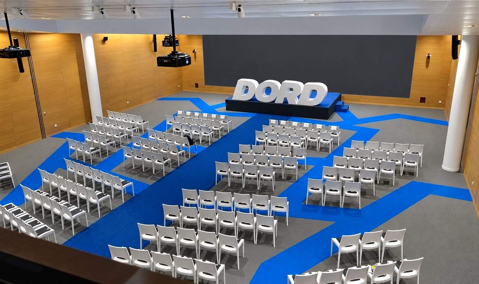 Salle de conférence avec chaises blanches et moquette bleue et grise