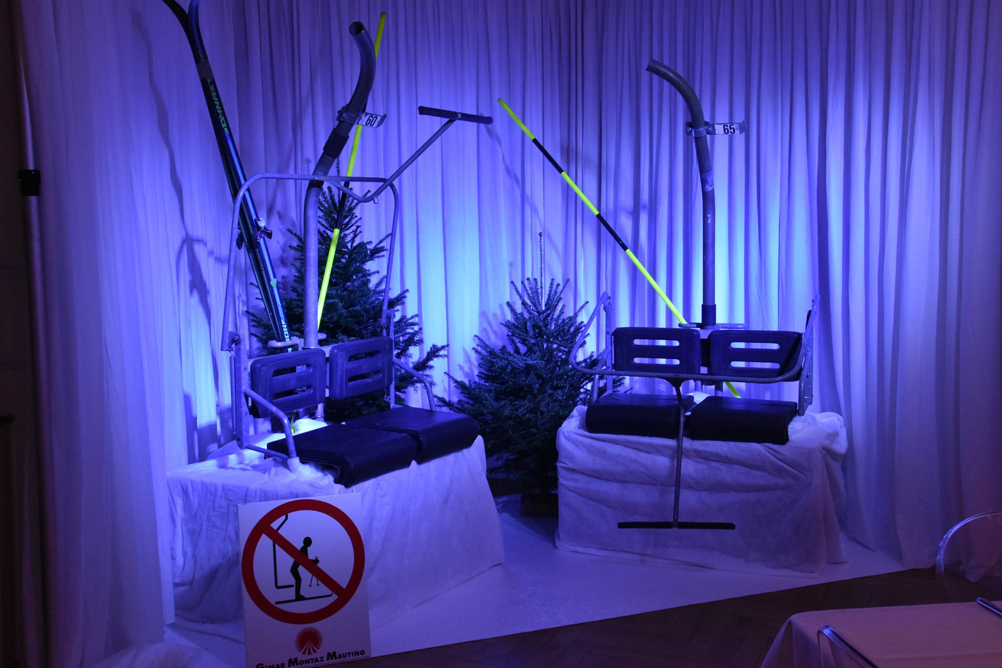 Deux sièges de télésiège décoratifs avec sapins et skis sous éclairage bleu