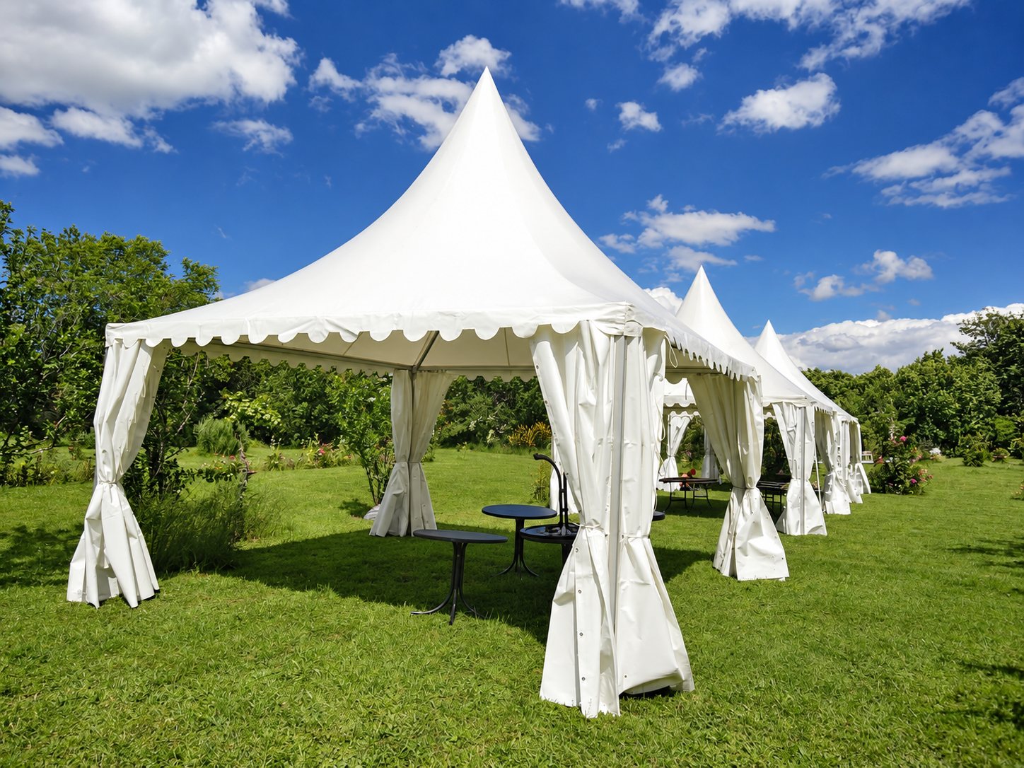 Tentes pagodes blanches installées sur une pelouse sous un ciel bleu