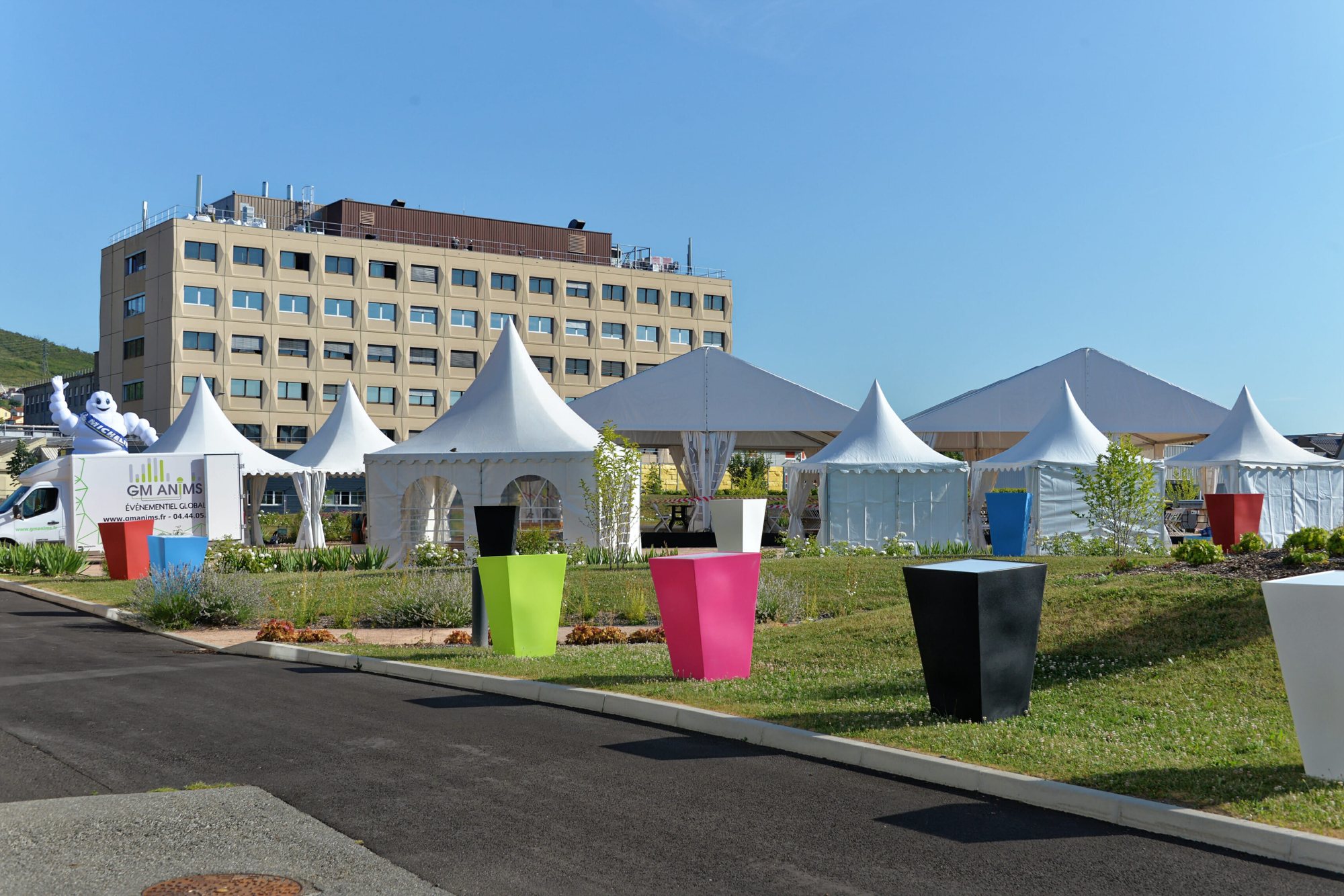 Tentes de réception blanches et grands pots colorés devant un bâtiment
