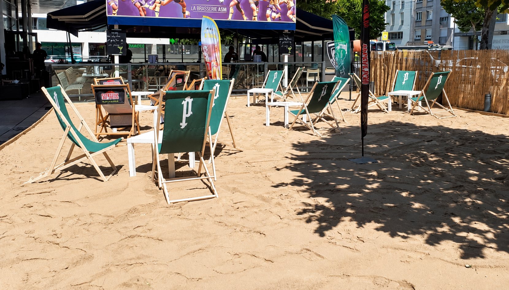 Terrasse de brasserie aménagée en plage avec chaises longues vertes